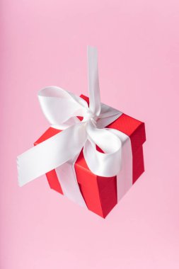 Beyaz kurdeleli küçük kırmızı hediye kutusu ve pembe arka planda fiyonk. çoklu uzay. Pankart. Tüm sevgililer ve anneler günü için hediye konsepti.