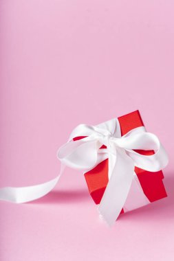 Beyaz kurdeleli küçük kırmızı hediye kutusu ve pembe arka planda fiyonk. çoklu uzay. Pankart. Tüm sevgililer ve anneler günü için hediye konsepti.