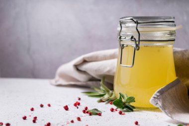 Seçici odaklanma. Cam kavanozda ev yapımı sığır eti çorbası. Açık gri arka planda. Baharat-tuz ve biber eklenerek. Kemikler kolajen içerir, bu da vücuda amino asit sağlar.