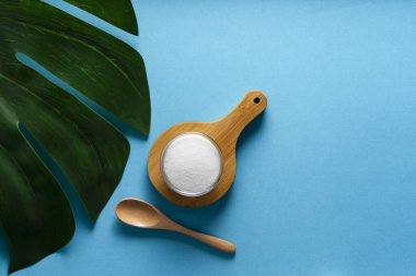 Seçici odaklanma. Cam bir kapta kolajen tozu. mavi düz arkaplan. çoklu uzay. Fazladan protein alımı. Cilt, kemik, eklem ve bağırsaklar için doğal güzellik ve sağlık desteği