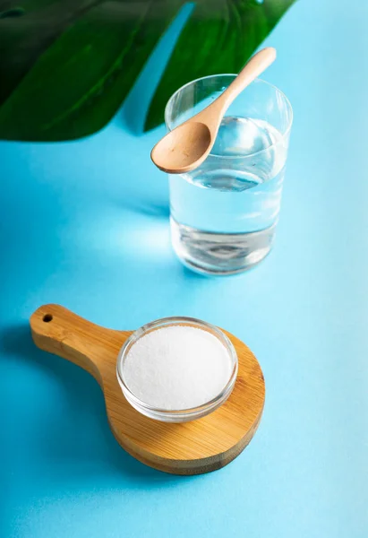 Seçici odaklanma. Cam bir kapta kolajen tozu. mavi düz arkaplan. çoklu uzay. Fazladan protein alımı. Cilt, kemik, eklem ve bağırsaklar için doğal güzellik ve sağlık desteği