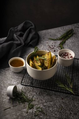 Köy patatesleri, dilimlenmiş, biberiyeli. Beyaz bir tabakta, koyu bir arka planda tereyağı ve baharatlarla. Bar ve restoran için menü kavramı