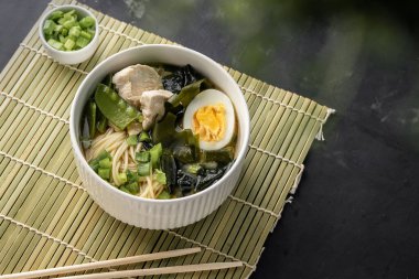 Tavuk ve yumurtalı erişteli Asya ramen çorbası. Koyu bir telif alanı arka planına taze soğan eklenerek, menüler ve tarifli makaleler için.