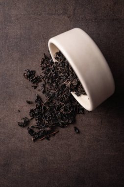Seçici odaklanma, doğal siyah yaprak çayı. Kil kasesinde demleniyor. Dikey açı, makro. Karanlık bir arka planda. Menüler ve kafeler için