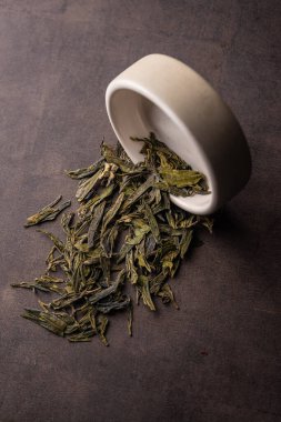 seçici odaklanma, doğal yeşil yaprak çayı. Kil kasesinde demleniyor. Dikey açı, makro. hafif bir arka planda. Menüler ve kafeler için