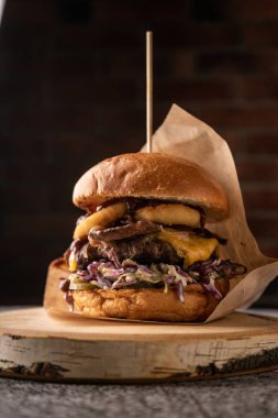 Taze sebze ve baharatlı sulu et burger. Yumuşak kokulu çörek ve doğal soslar. Yan görünüş. Koyu bir arkaplanda, menüler ve reklamlar için