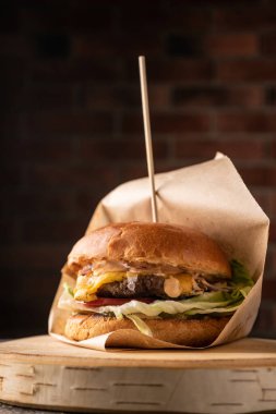 Taze sebze ve baharatlı sulu et burger. Yumuşak kokulu çörek ve doğal soslar. Yan görünüş. Koyu bir arkaplanda, menüler ve reklamlar için