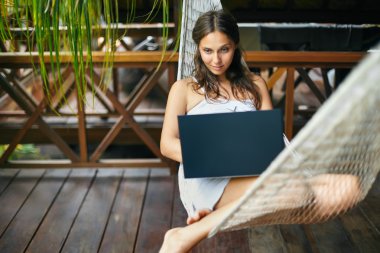 dizüstü bilgisayar ile bir hamakta yatan kadın