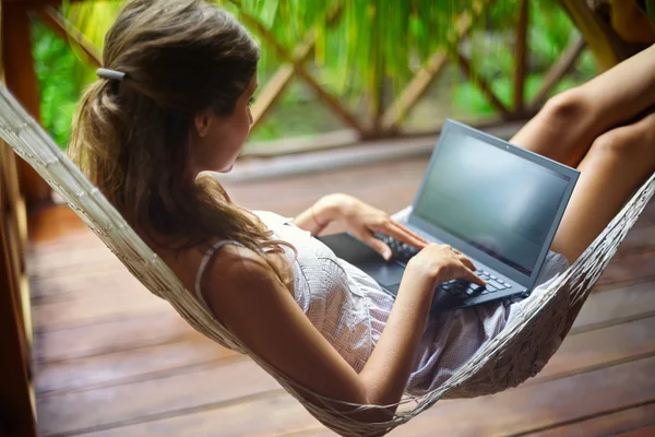 Kvinna i en hängmatta med laptop — Stockfoto