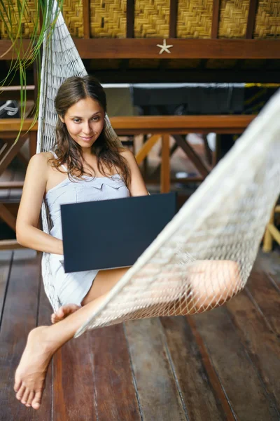 Frau liegt mit Laptop in Hängematte — Stockfoto