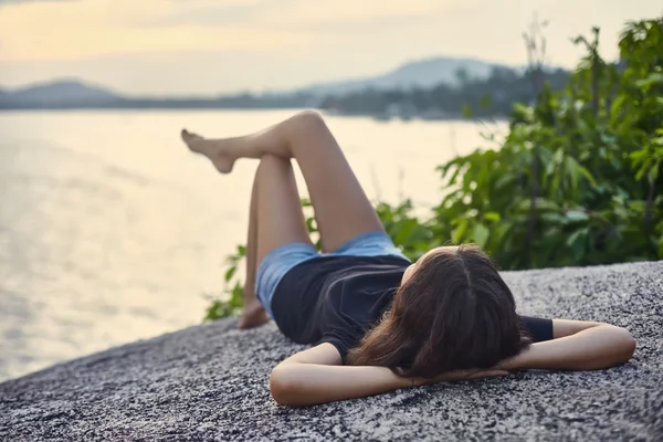 Junge Frau entspannt sich auf Klippe — Stockfoto