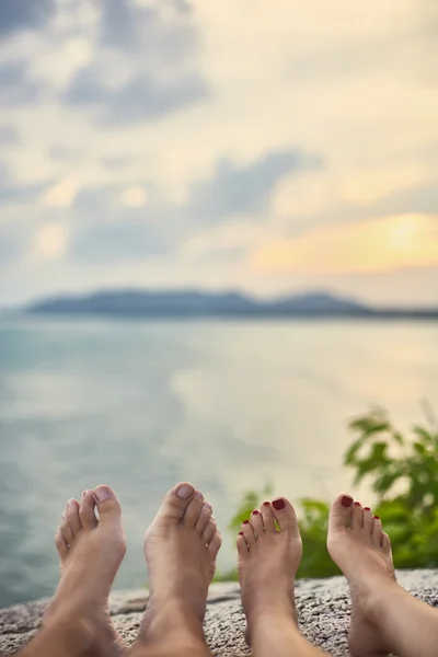 Picioarele cuplului se relaxează pe vârful muntelui cu vedere la mare — Fotografie, imagine de stoc