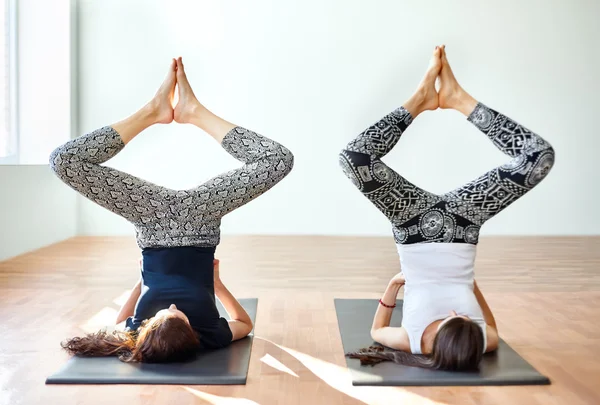 Two young women doing yoga asana bound angle shoulderstand pose — Stock Photo, Image