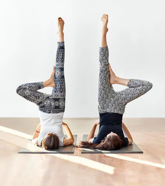 Dvě mladé ženy dělají yogové ásány podporované shoulderstand — Stock fotografie