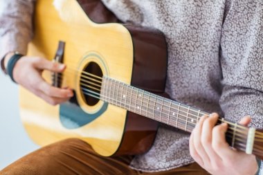 Adamın elleri akustik gitar çalıyor.