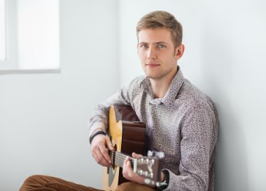 yakışıklı adam katta oturan gitar çalmak