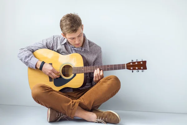 Handsome man playing guitar sitting on floor — Stock Photo, Image