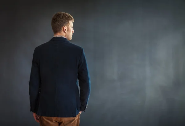 Jeune homme debout contre un mur gris — Photo