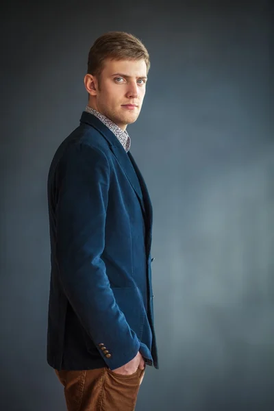 Hombre guapo de pie contra la pared gris — Foto de Stock