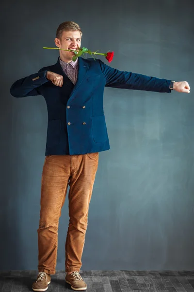 Handsome man dancing with a red rose in his mouth — Stock Photo, Image