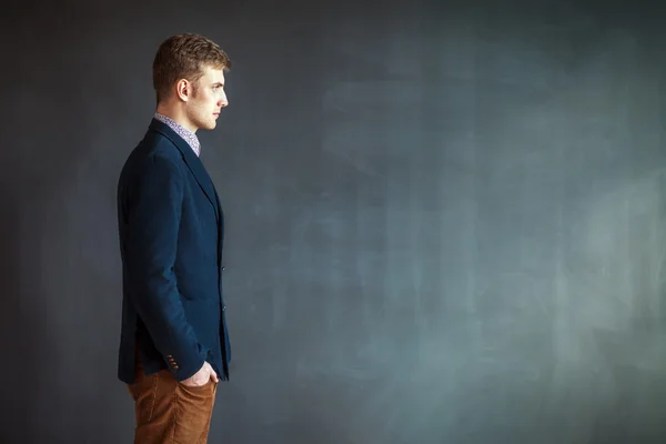 Stilig man står mot grå vägg bakgrund — Stockfoto