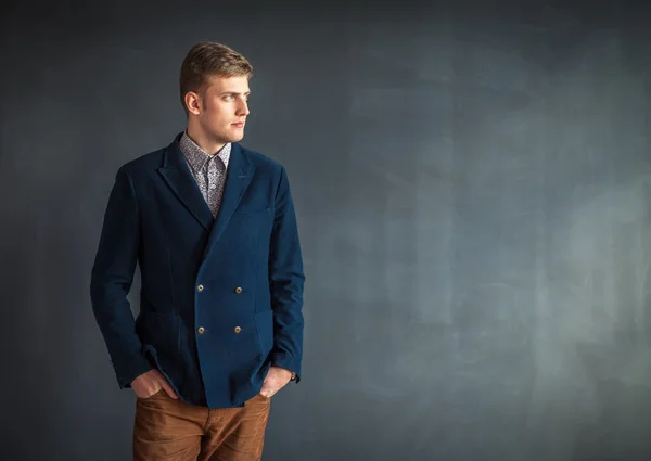 Guapo hombre serio de pie contra la pared gris — Foto de Stock