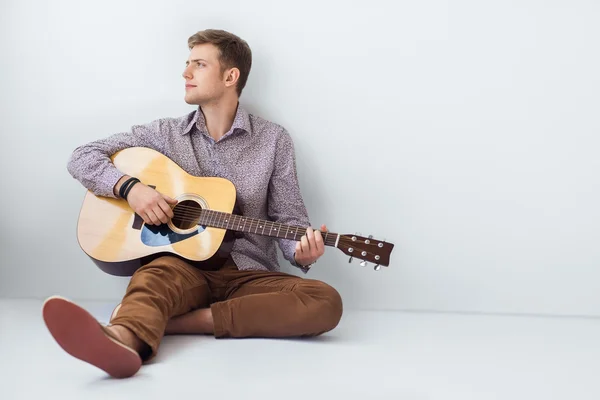 Mężczyzna gra na gitarze, siedząc na podłodze — Zdjęcie stockowe