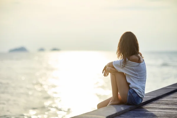 Junge schöne Frau sitzt auf Pier — Stockfoto