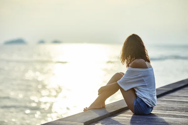 Junge schöne Frau sitzt auf Pier — Stockfoto