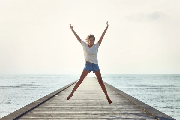 Happy jumping girl on pier — Stock Photo, Image