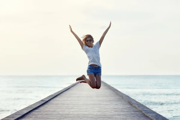 Gelukkig springen meisje op de pier — Stockfoto