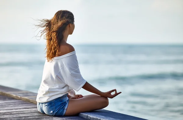 Frau meditiert in Lotus-Pose auf Pier — Stockfoto