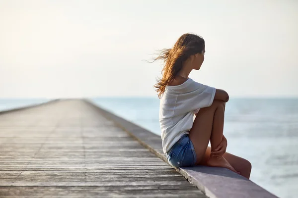 Young beautiful woman sitting on pier — Stock Photo, Image