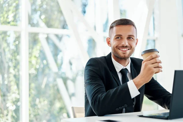 Feliz hombre de negocios guapo relajarse con la taza de café en la mano durante el tiempo de descanso en la oficina moderna con espacio para copiar —  Fotos de Stock