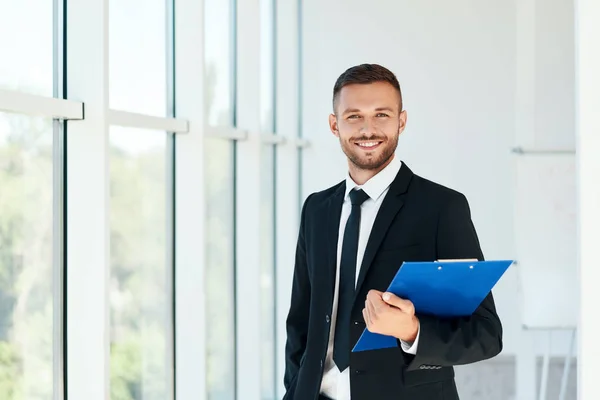 Bello uomo d'affari sorridente con appunti in un luminoso ufficio moderno — Foto Stock