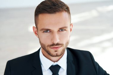 Zarif takım elbiseli yakışıklı, gülümseyen genç adamın yakın portresi.