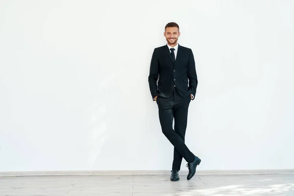 Sorrindo confiante empresário em elegante suíte posando no fundo da parede branca — Fotografia de Stock