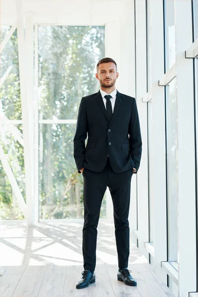 Retrato de larga duración del hombre de negocios confiado en elegante suite posando en la oficina creativa moderna — Foto de Stock