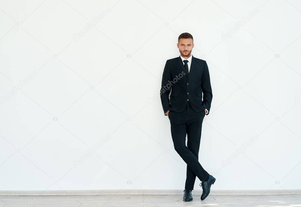 Full length portrait of confident businessman in elegant suite posing on white background
