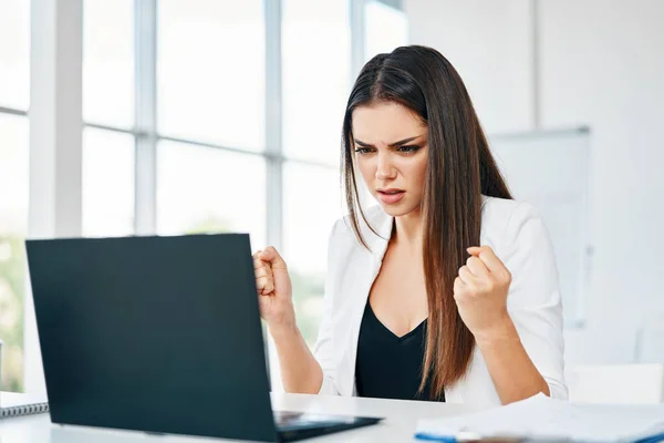 Empresária chocada olhando para laptop lendo más notícias em sua mesa no escritório moderno — Fotografia de Stock