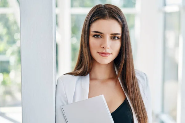 Selbstbewusste Geschäftsfrau mit Dokumenten und Blick in die Kamera in modernem Kreativbüro — Stockfoto