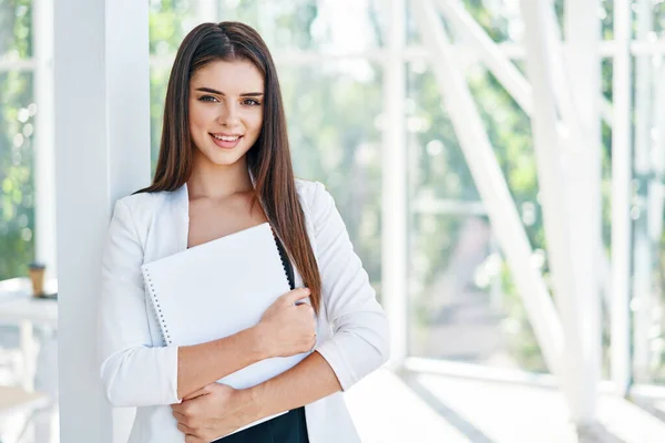 Mujer de negocios confiada sosteniendo documentos y mirando a la cámara en la oficina creativa moderna — Foto de Stock