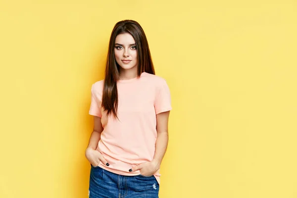 Portrait of beautiful cheerful young woman in casual on yellow background with copy space. — Stock Photo, Image