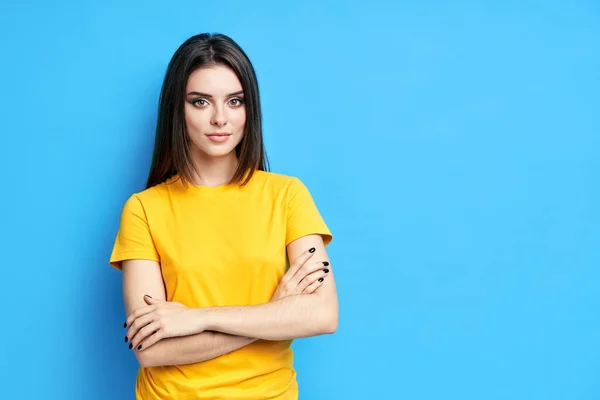 Ganska säker ung vacker kvinna i casual kläder med korsade armar över blå bakgrund — Stockfoto