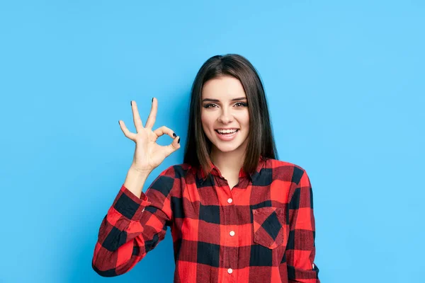 Leende kvinna gesterande ok tecken på blå bakgrund — Stockfoto