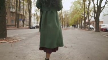 Yörüngede gülümseyen Asyalı kadının akıllı telefonuyla müzik dinlediği ve kahve içtiği bir fotoğraf var.