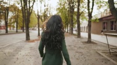 Genç ve güzel bir kadın sokakta yürüyor ve kamerada flört ediyor.