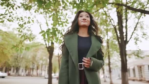 Feliz sorrindo asiático mulher andando e girando ao redor no o cidade rua no ensolarado dia — Vídeo de Stock