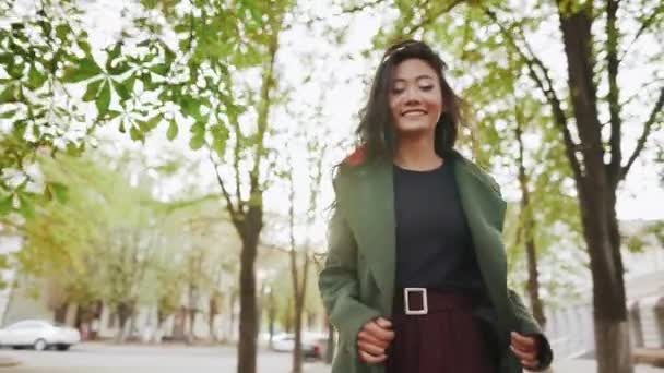 Улыбающаяся азиатка ходит и разворачивается по городской улице в солнечный день — стоковое видео