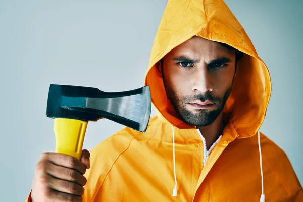 Retrato de hombre guapo brutal en impermeable brillante sosteniendo hacha grande —  Fotos de Stock